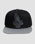 Front view of the ‘Men’s Prayer Skull Roses Snapback’ by Ring of Fire Clothing in Black Grey color, showcasing the unique design of prayer hands with roses and skulls inside the roses, in one size.
